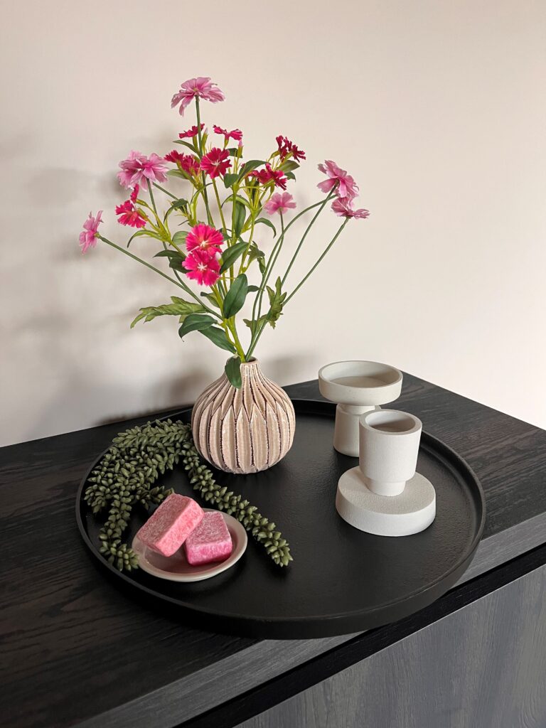 Zwart dienblad met vaasje en roze boeketje. Set voor op tafel, salontafel of TV-meubel