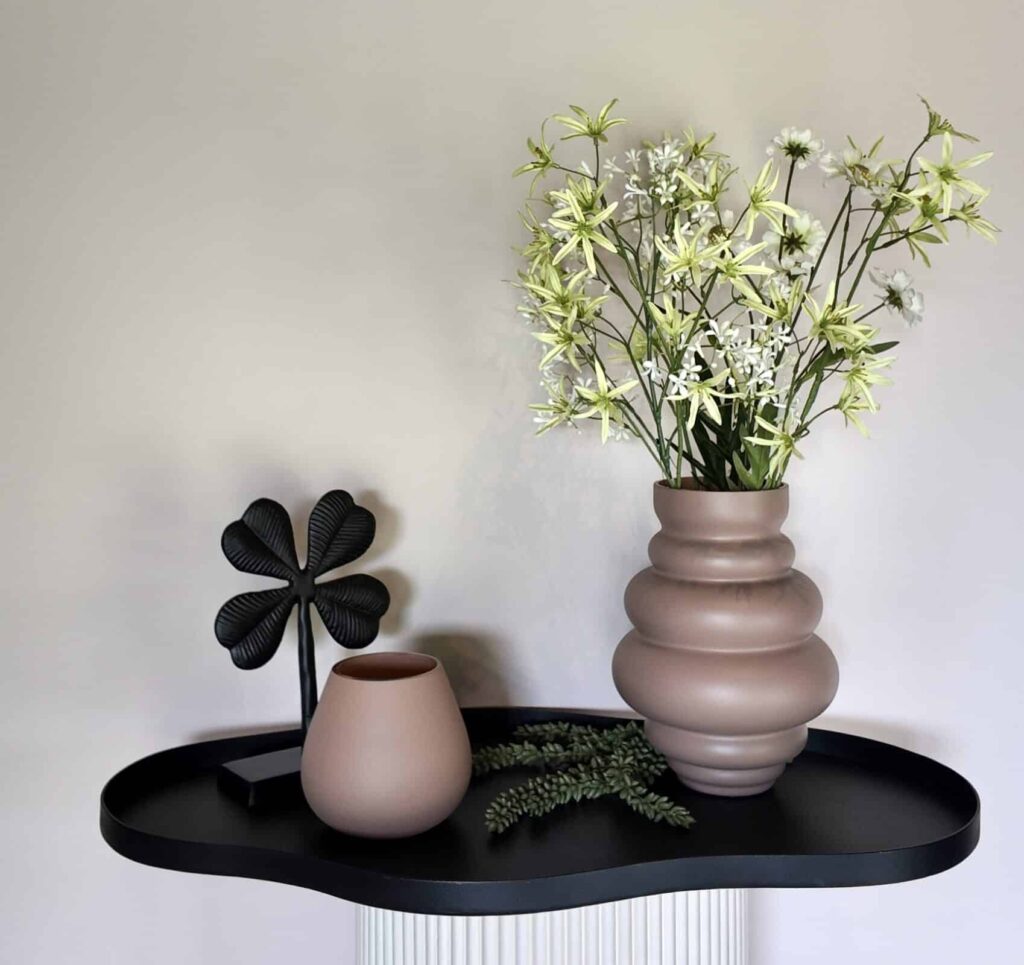 Zijden bloemen in mooie zand kleur vaas op zwart groot dienblad